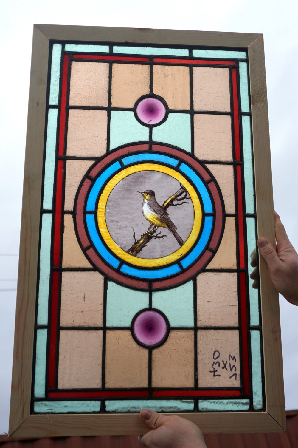 a good stained glass window with painted bird to the centre